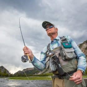 man fly fishing under cloudy skies